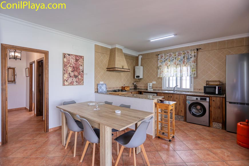 Cocina con mobiliario de madera, barra americana y electrodomésticos