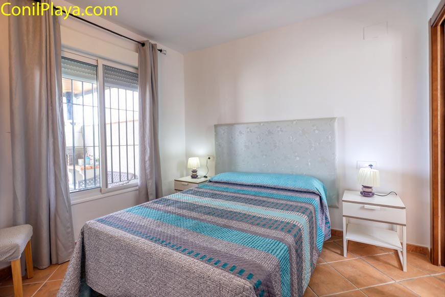 Dormitorio con cama de matrimonio, cabecero tapizado y mesitas