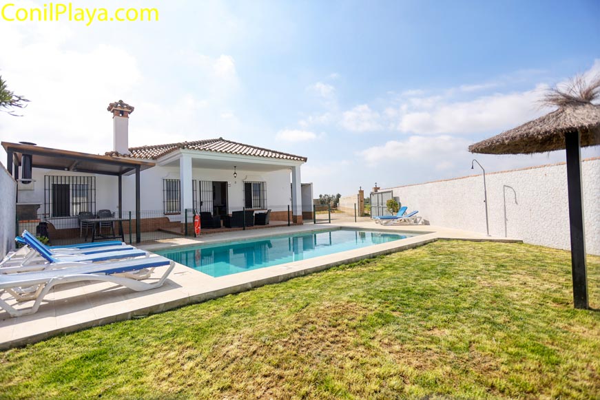 Vista general del jardín, piscina y fachada del alojamiento