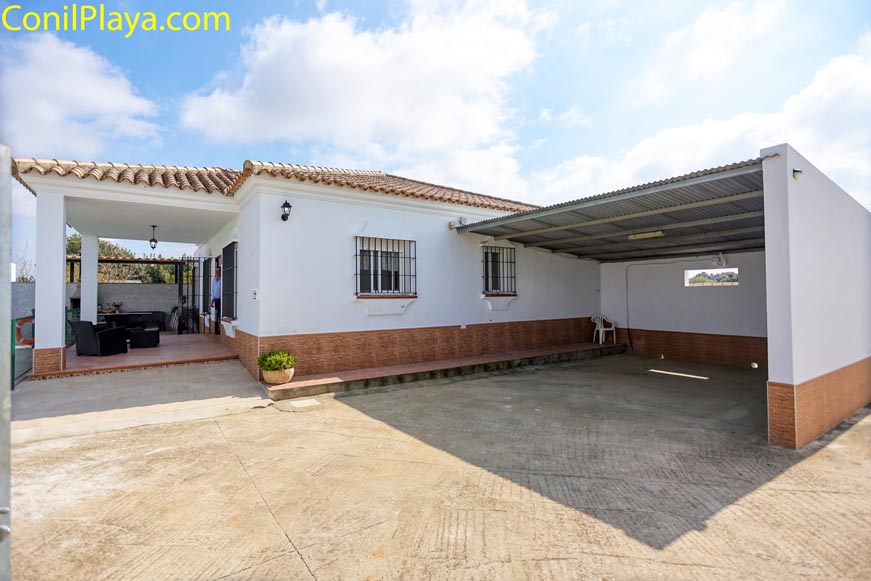 Vista exterior de la casa con porche delantero y zona de aparcamiento techado