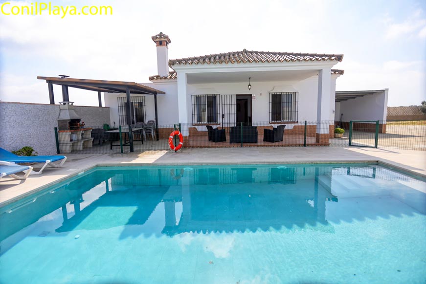 Vista general de la piscina vallada con la casa al fondo