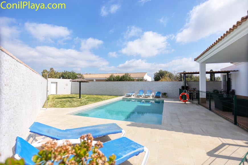Piscina privada con valla de seguridad infantil y tumbonas azules