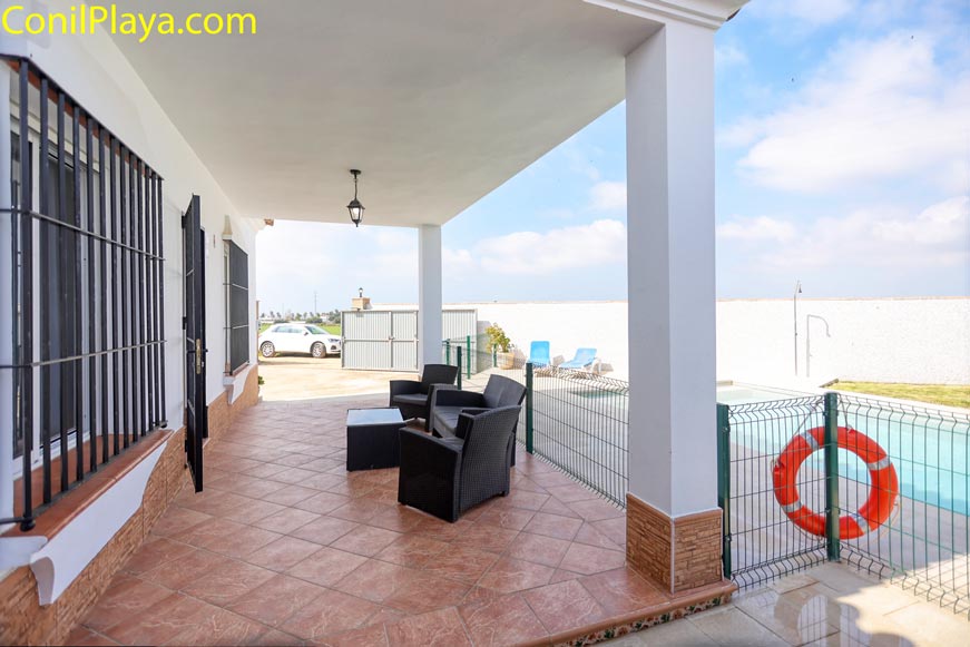 Porche cubierto con sofás de exterior frente a la piscina