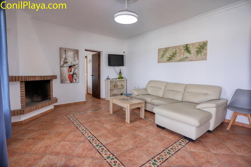 Acogedor salón con sofá de piel beige y chimenea de obra