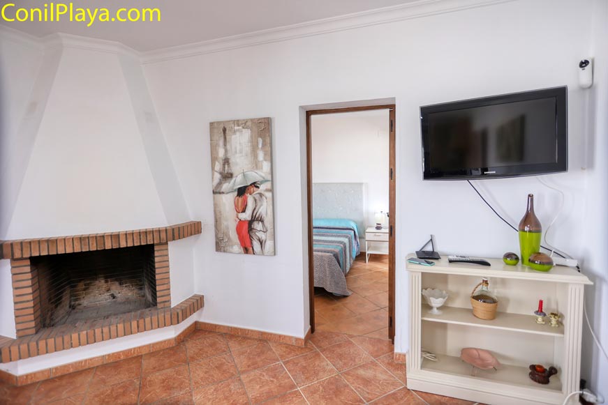 Zona de estar con chimenea, televisión y paso a dormitorio