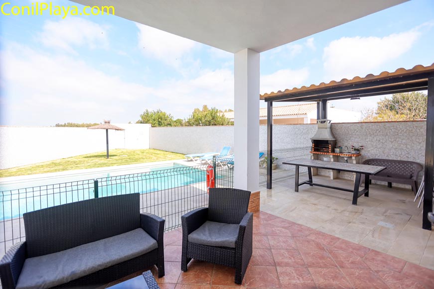 Vista panorámica desde el porche hacia la piscina y zona de barbacoa