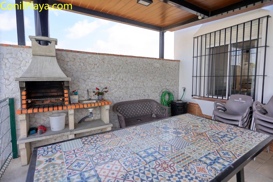 Zona de barbacoa de obra con mesa de mosaico en porche cubierto