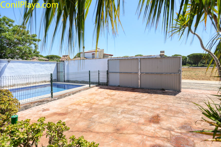 Aparcamiento privado junto a piscina y cancela visto desde patio exterior