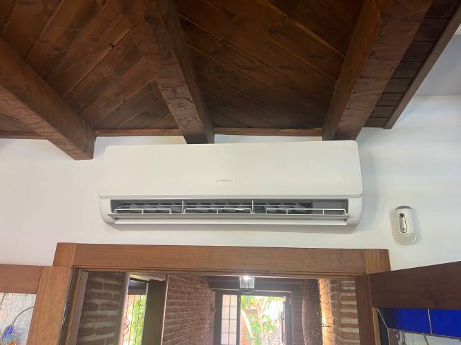 Aire acondicionado en salón con techo de madera y puerta abierta
