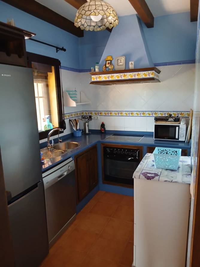 Cocina pequeña con encimera azul y electrodomésticos modernos visibles desde la puerta