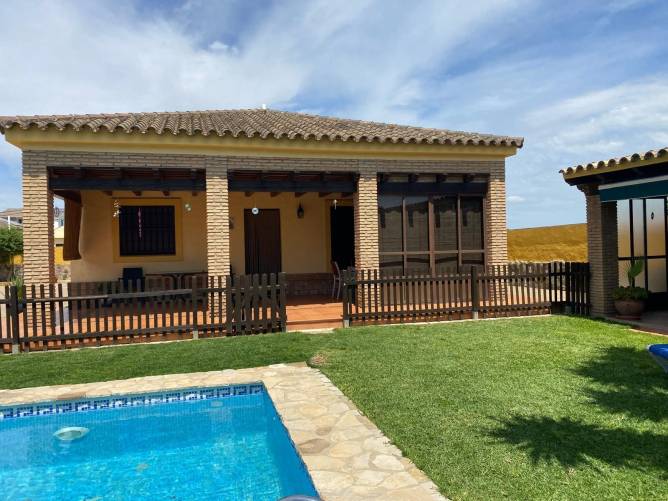 Vista desde el jardín del chalet con piscina vallada y porche amplio