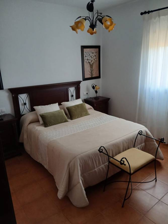 Dormitorio con cama de matrimonio, luz natural y decoración sencilla