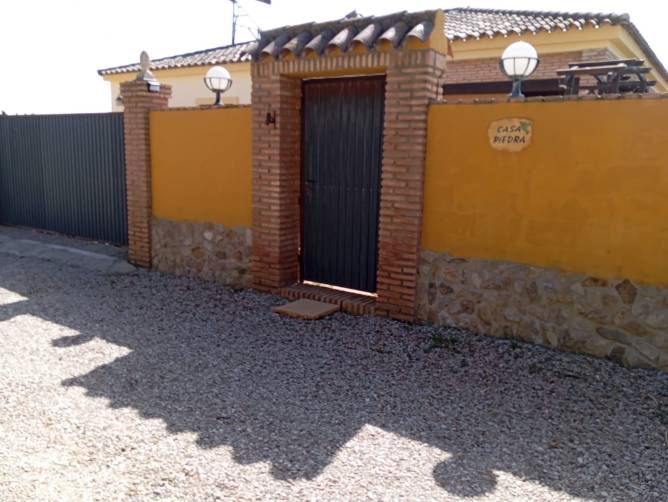 Fachada de la entrada principal con muro de piedra y puerta
