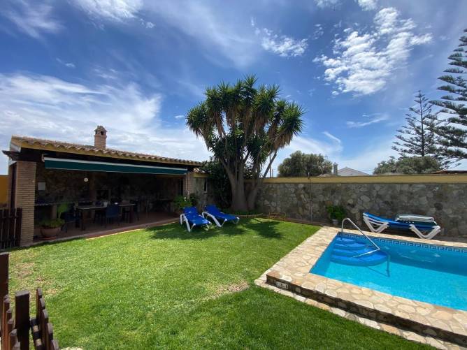 Jardín con piscina y barbacoa junto a terraza vista desde el césped