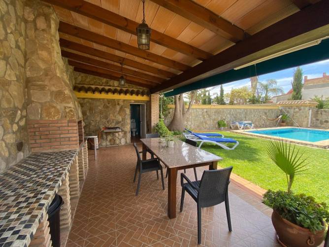 Porche cubierto con mesa junto a piscina y zona de barbacoa privada