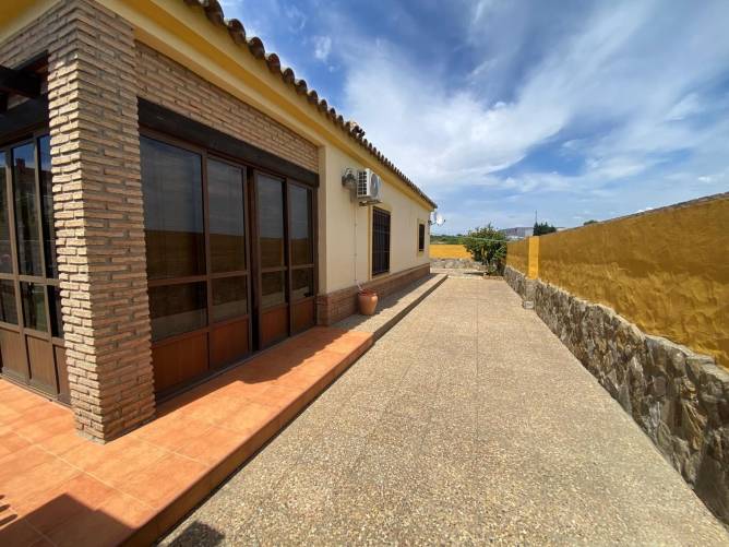 Patio lateral amplio con suelo de piedra y macetas decorativas