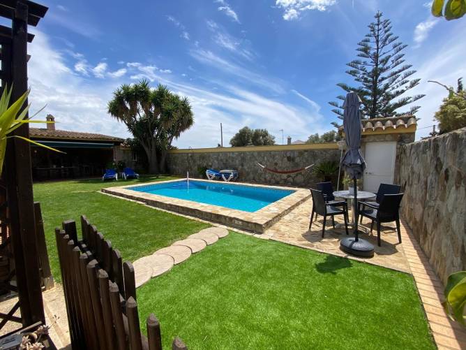 Zona exterior con piscina privada y césped rodeada de muro de piedra