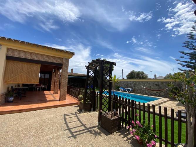 Vista desde el porche de una piscina vallada junto a terraza y jardín