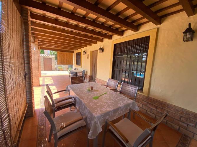 Porche amplio con mesa y sillas junto a la fachada de la vivienda