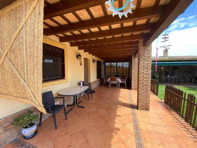 Vista de un amplio porche con mesas y sillas en vivienda