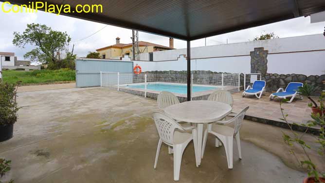 porche con mesa y sillas y al fondo la piscina