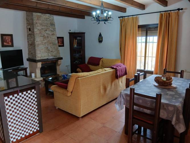 Salón con chimenea, sofá en L y mesa de comedor visto desde la entrada