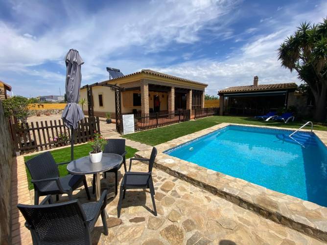 Terraza con mesa y sillas junto a piscina y vivienda en primer plano