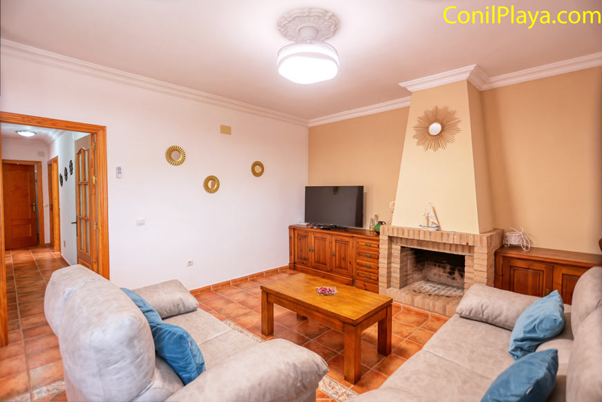 Vista del salón con chimenea, televisión plana y ventilador de techo