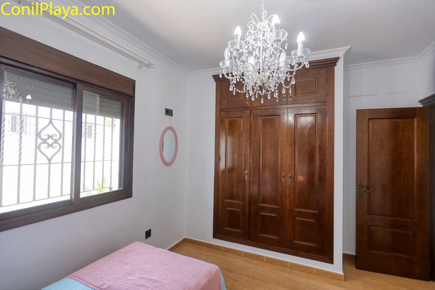 Dormitorio con armario empotrado ventana y lámpara de techo