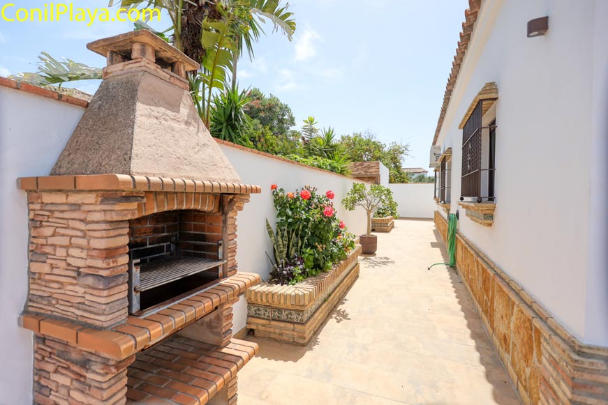 Barbacoa de obra junto a la fachada y plantas en maceteros