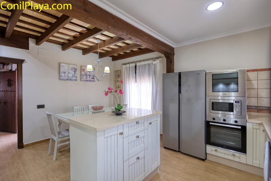 Cocina luminosa con isla central, electrodomésticos modernos y mesa de comedor pequeña