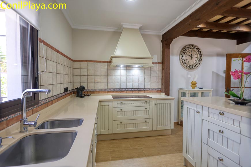 Cocina luminosa con muebles blancos fregadero doble y extractor sobre vitrocerámica