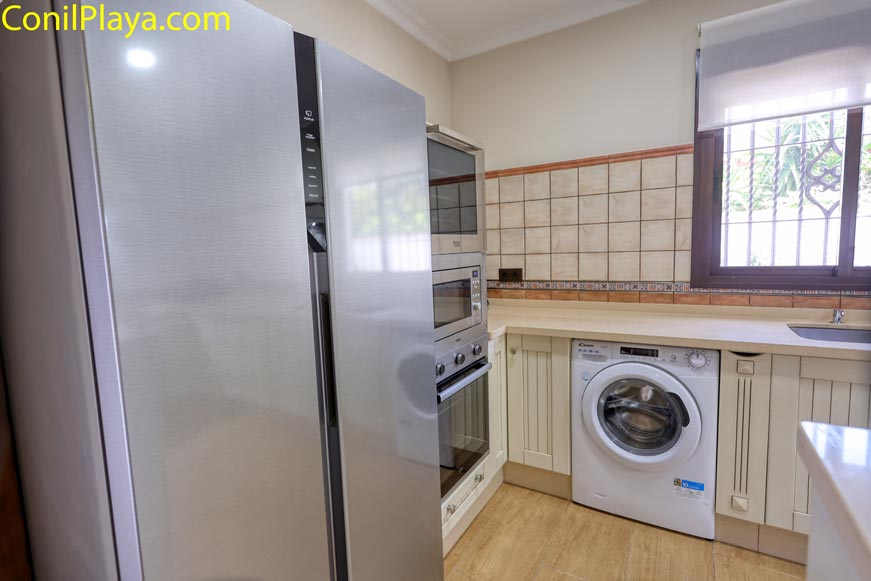 Cocina moderna con electrodomésticos y lavadora junto a una ventana