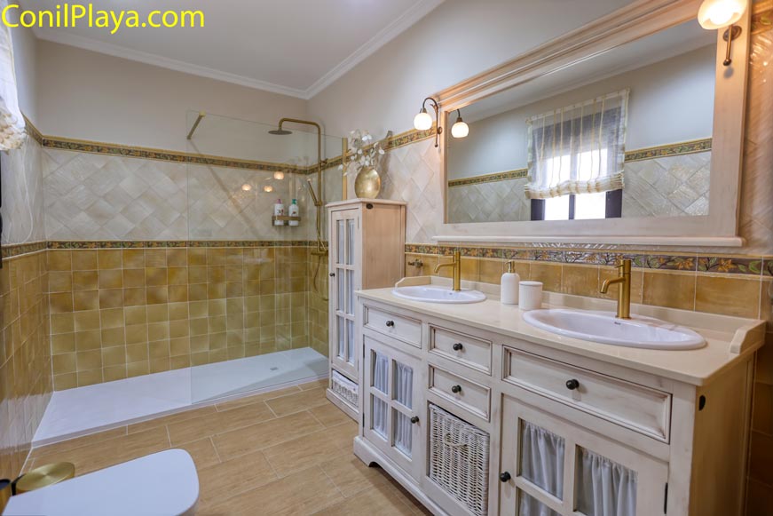Cuarto de baño amplio con ducha, dos lavabos y muebles rústicos