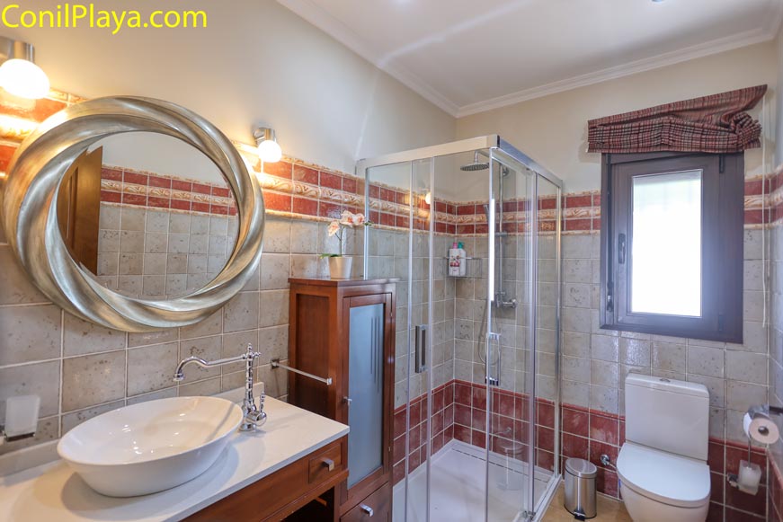 Cuarto de baño con ducha mampara ventana y lavabo de encimera