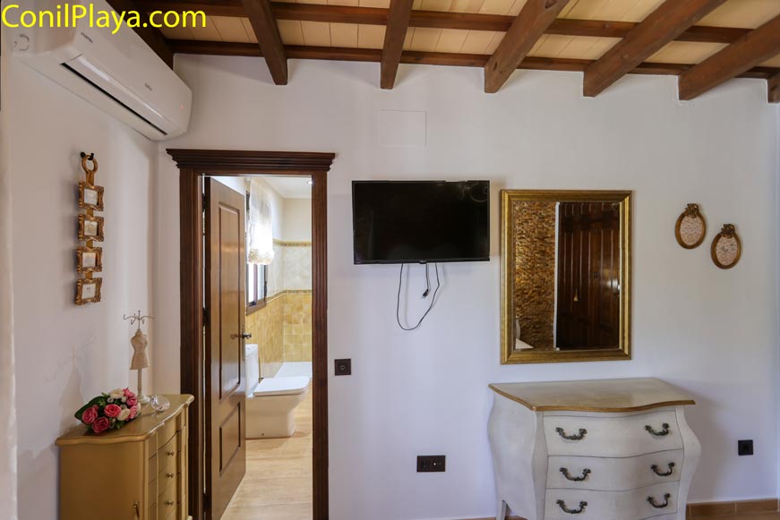 Dormitorio con aire acondicionado, televisión y muebles clásicos de madera