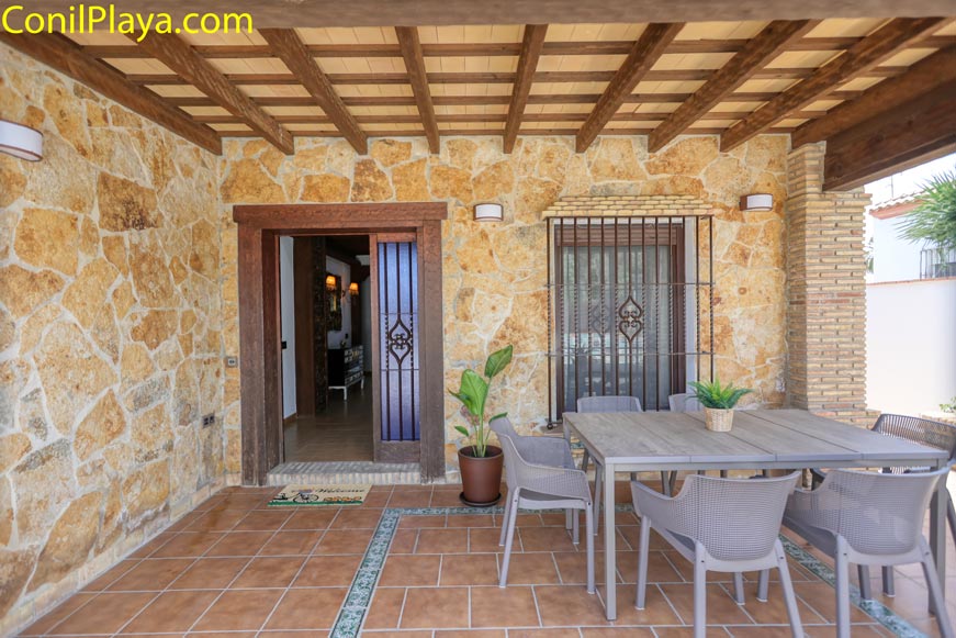 Porche cubierto con mesa y sillas junto a la entrada principal de la casa