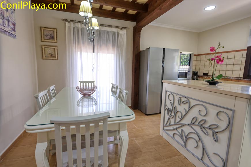 Cocina con isla decorativa y mesa comedor de cristal con seis sillas blancas