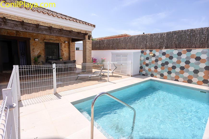 Piscina privada vallada junto al porche y zona de tumbonas exterior