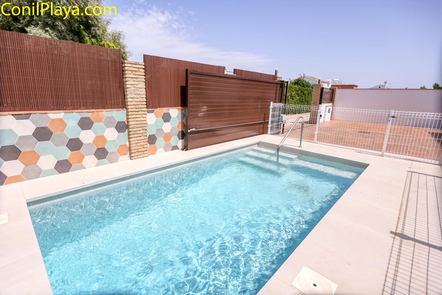 Piscina vallada junto a pared decorada en vivienda vacacional
