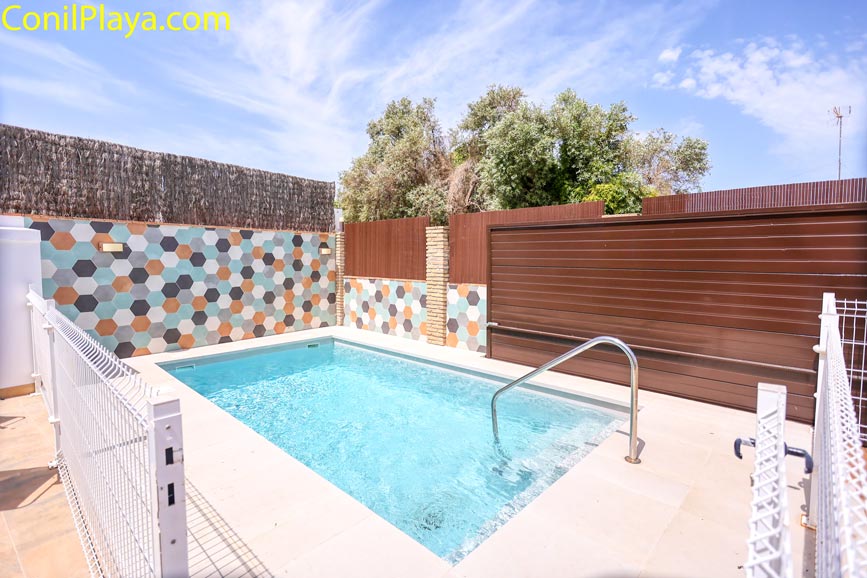 Pequeña piscina vallada junto a pared con mosaicos vista desde la entrada