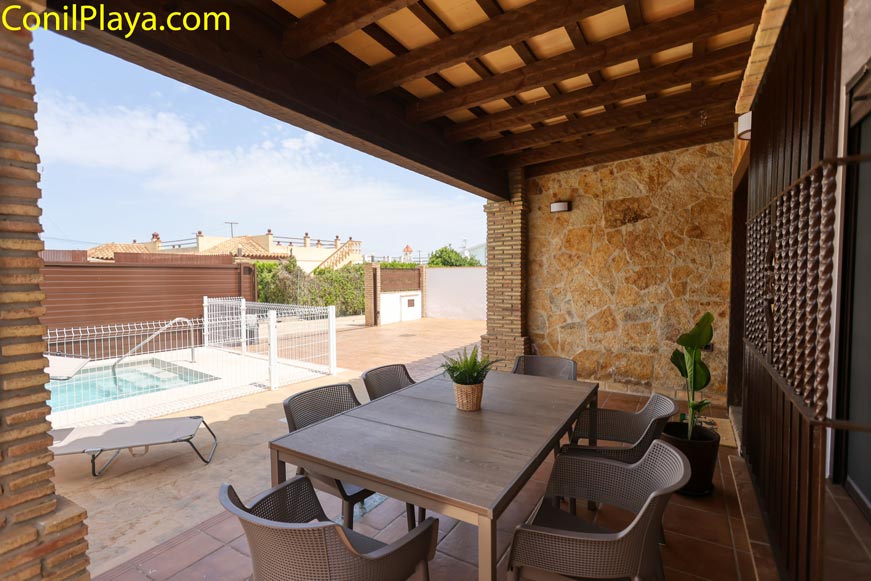 Porche con mesa y sillas junto a piscina vallada vista desde dentro