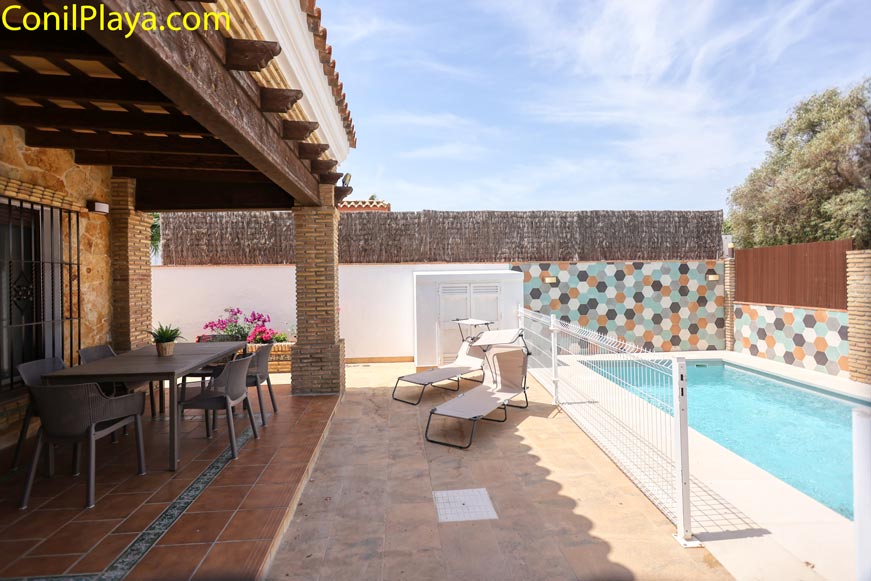 Vista del porche con mesa y sillas junto a piscina privada rectangular