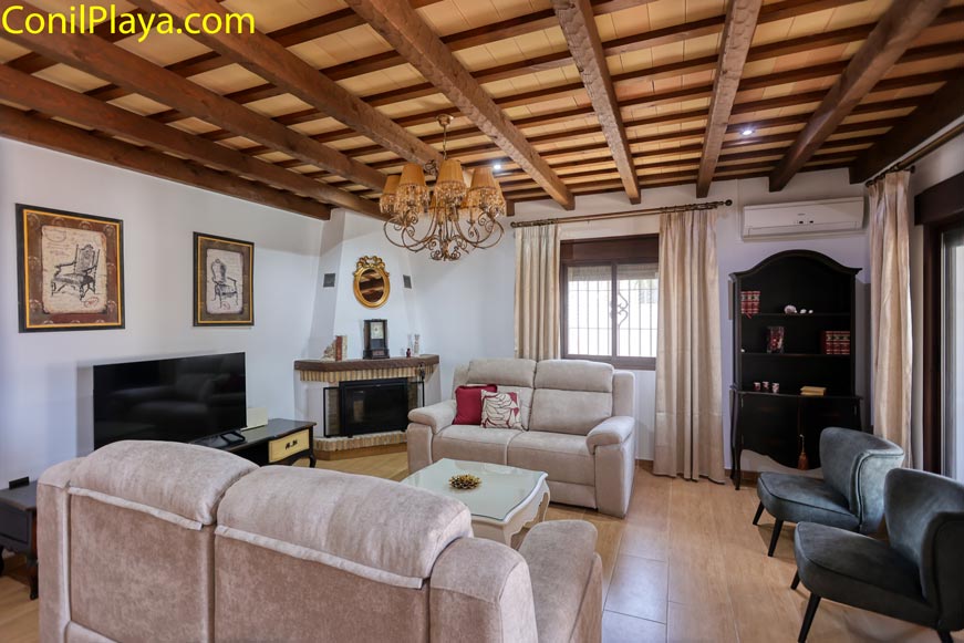 Salón acogedor con sofás beige, chimenea y vigas de madera vista