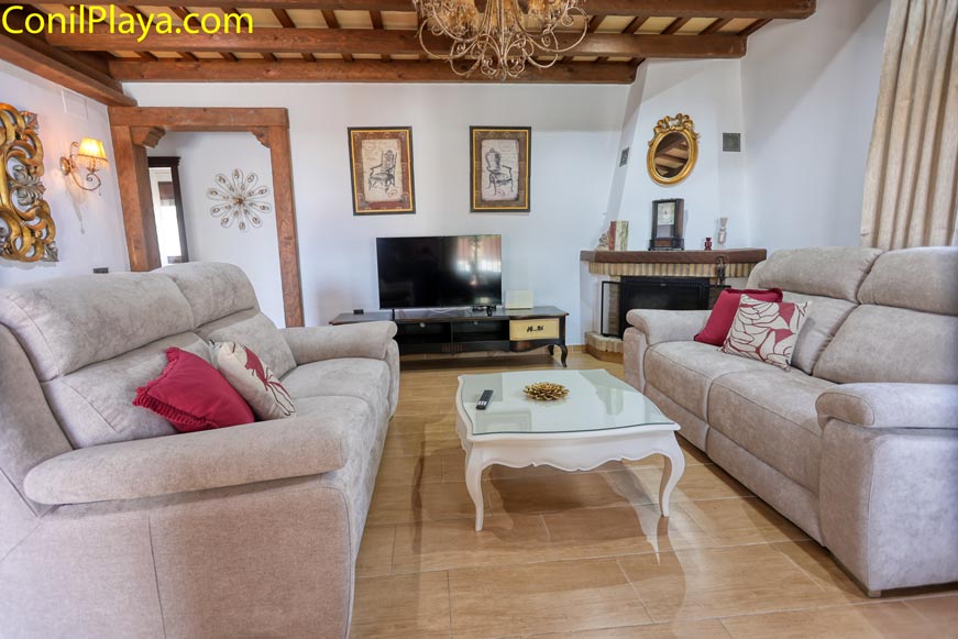 Salón con dos sofás beige, chimenea, mesa central y televisión frente