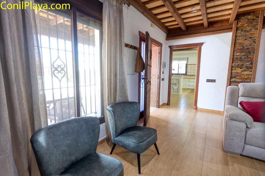 Salón con sillones, ventanales y techo de vigas de madera