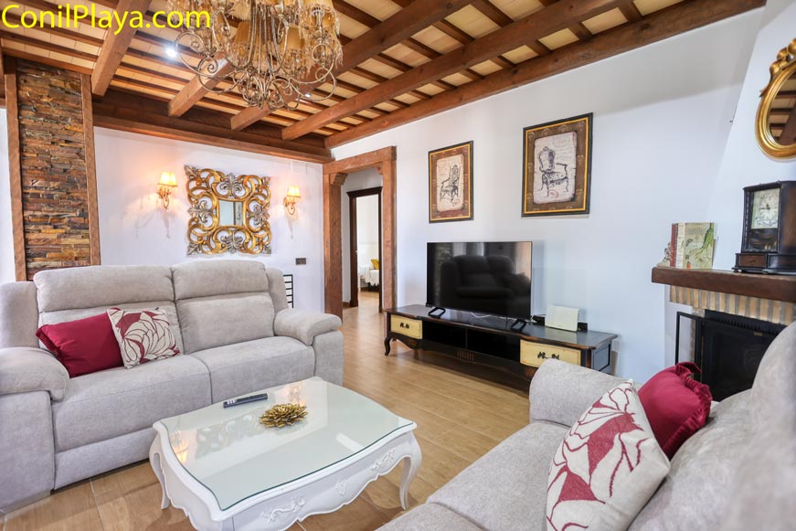 Salón amplio con sofá gris, mesa blanca y televisión al fondo