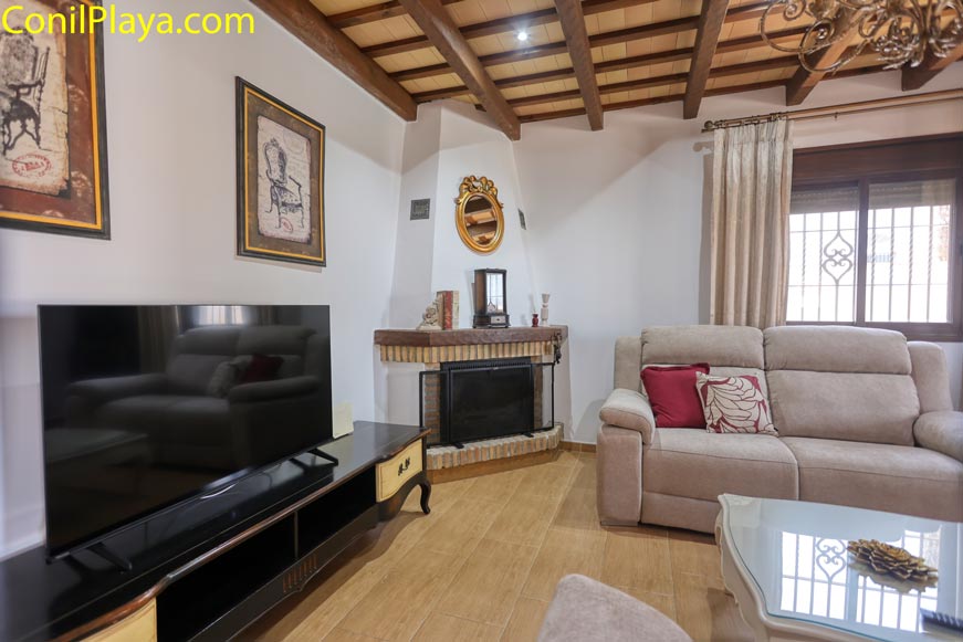 Salón acogedor con televisor, chimenea y sofá visto desde la entrada