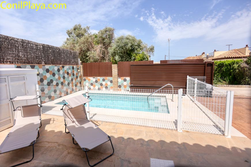 Zona exterior con piscina vallada y tumbonas junto a una vivienda
