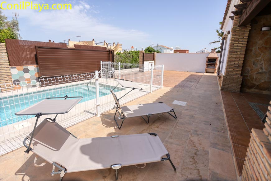 Zona exterior con piscina y tumbonas junto a una casa de ladrillo